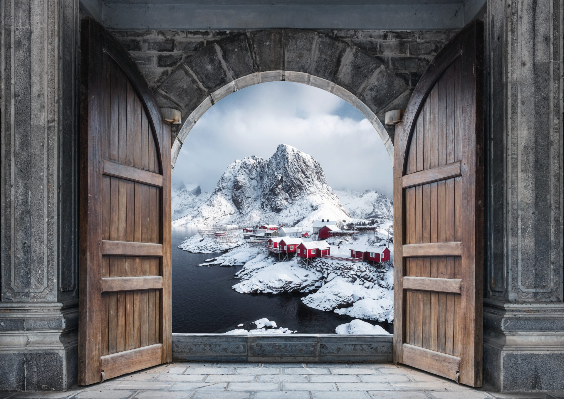 Large wooden door open with fishing village and rocky mountains